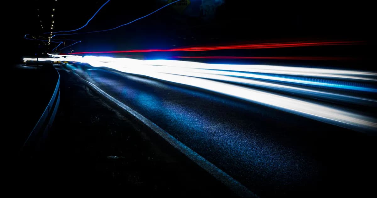 Long exposure shot of vibrant light trails on a highway at night, showing urban motion and speed