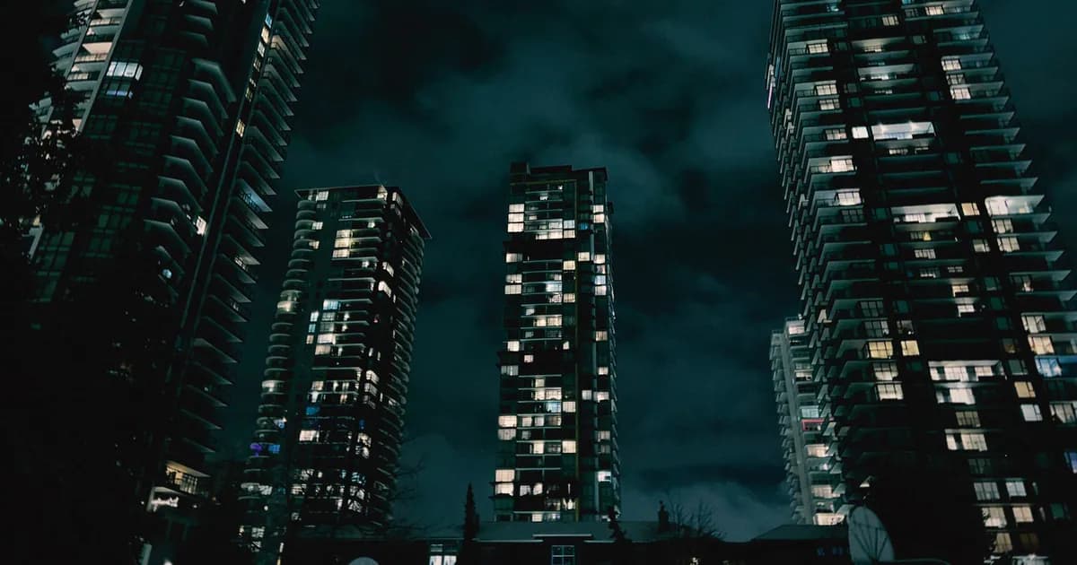 Illuminated skyscrapers towering against a dark, cloudy night sky