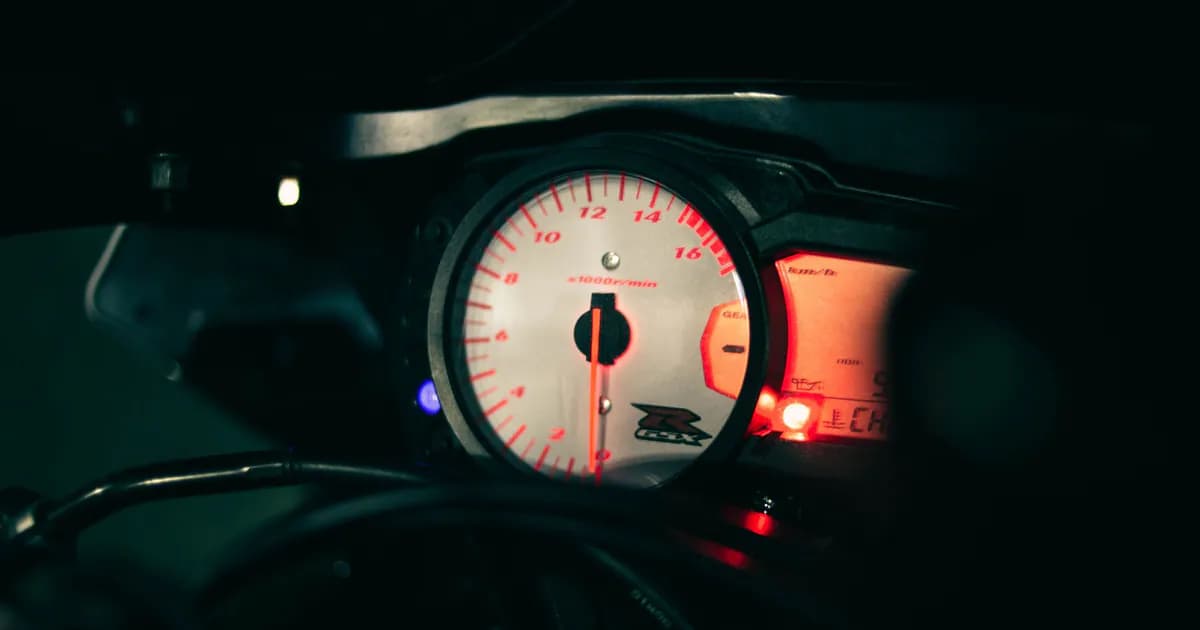 A detailed view of a motorcycle speedometer illuminated in the dark