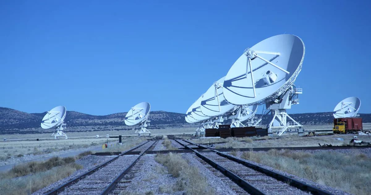 Array of satellite dishes in rural landscape with clear blue sky