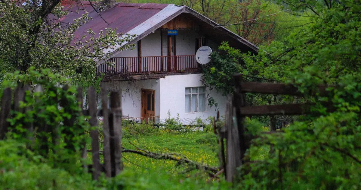 A charming rustic house enveloped by lush spring greenery and natural wooden fences