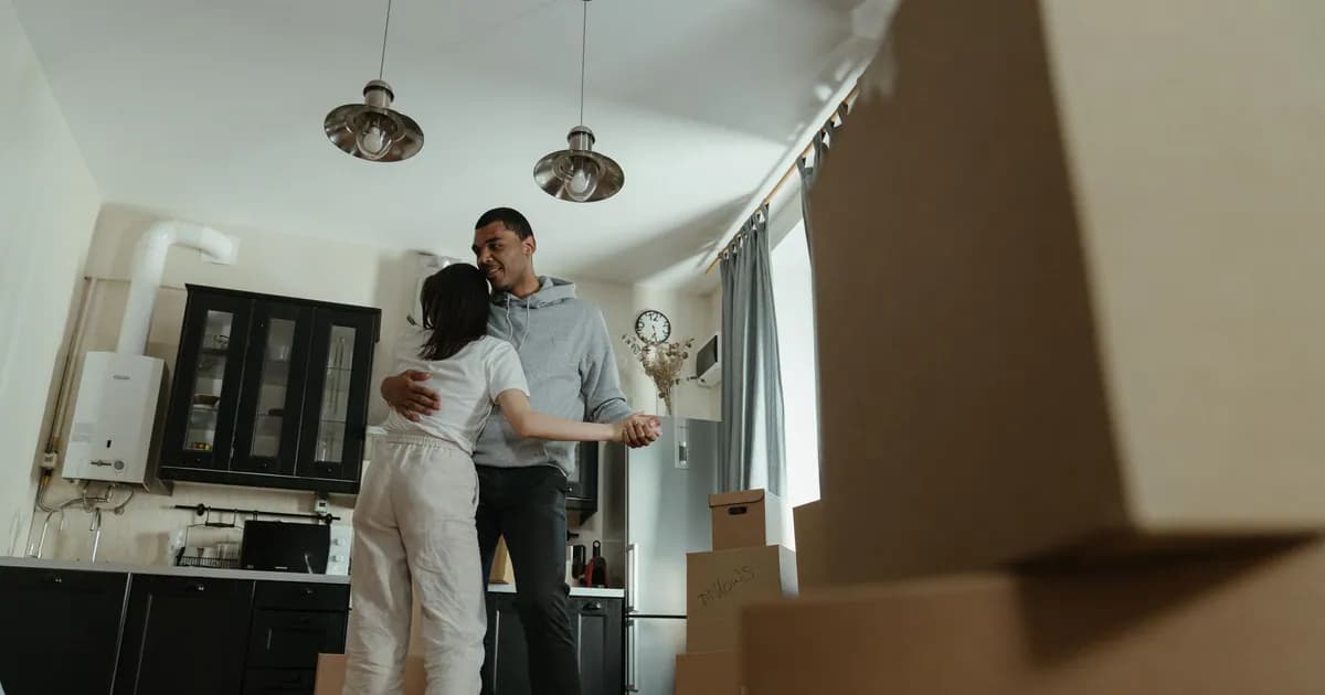 Happy couple dancing together in their new home filled with moving boxes, celebrating new beginnings