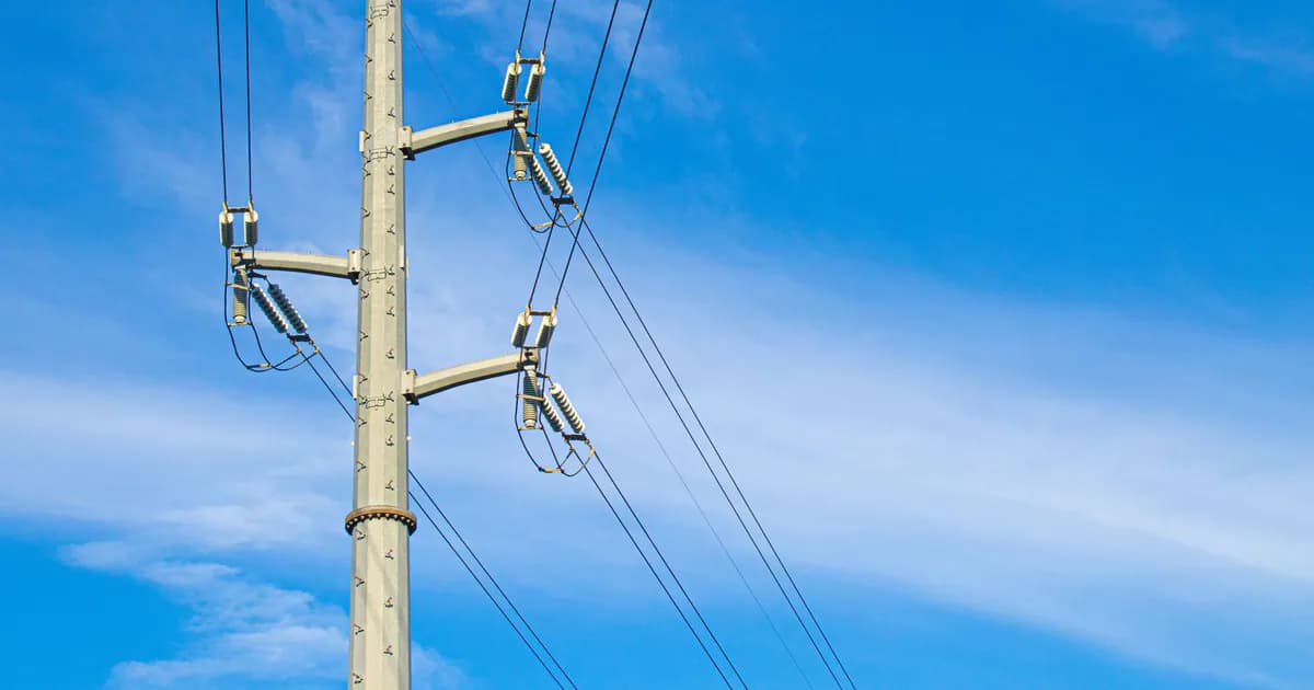 A utility pole with power lines set against a bright blue sky