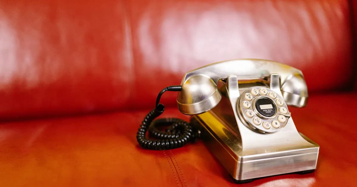 Close-up of a classic rotary phone on a red leather chair