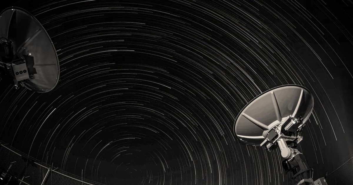 Long exposure of star trails creating circular patterns over two satellite dishes against a night sky
