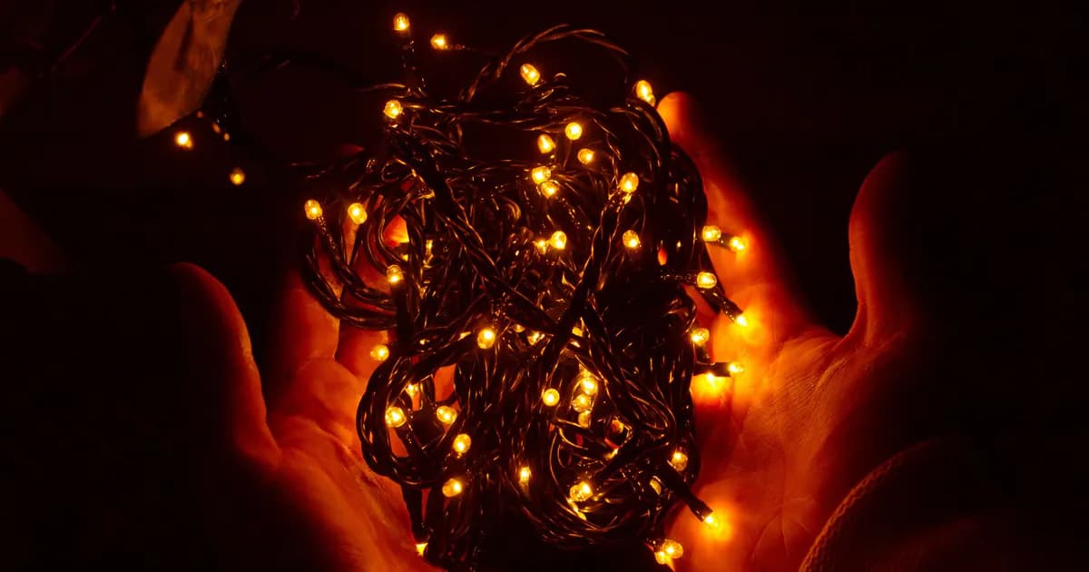 Hands gently holding glowing Christmas lights, creating a warm festive atmosphere