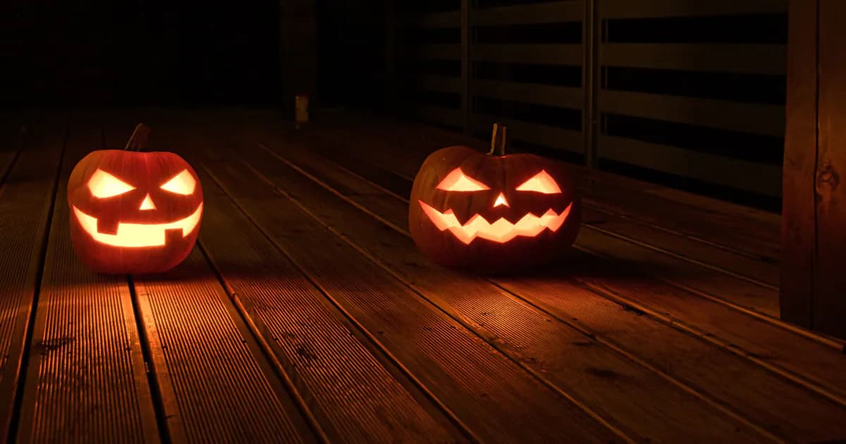 Illuminated jack-o-lanterns with carved faces create a spooky Halloween ambiance on a wooden deck at night