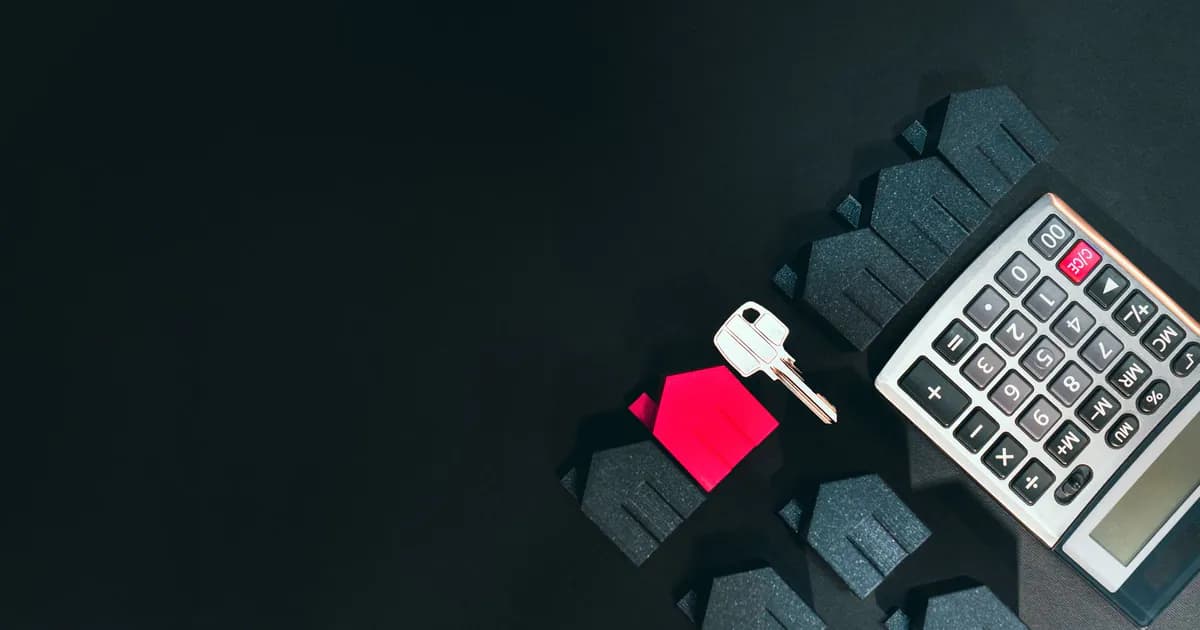 Real estate concept image featuring a calculator, houses, and a key on a black background