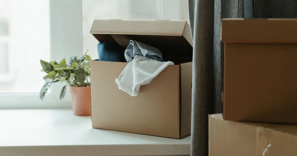 Open cardboard box with clothes by window