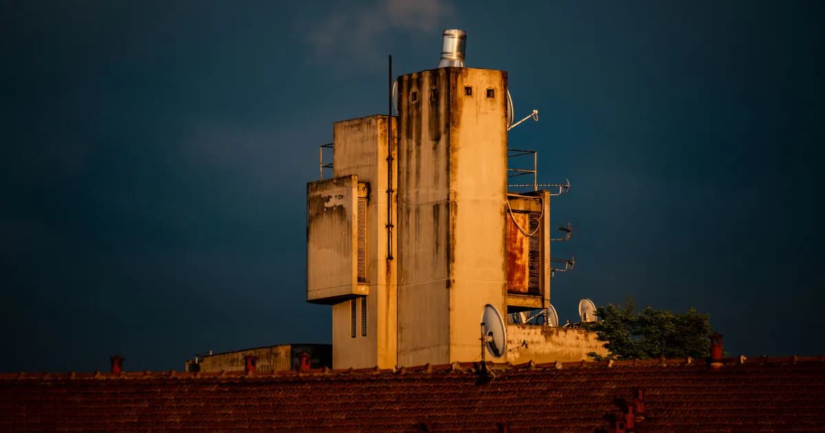 An industrial building with antennas on a rooftop during sunset