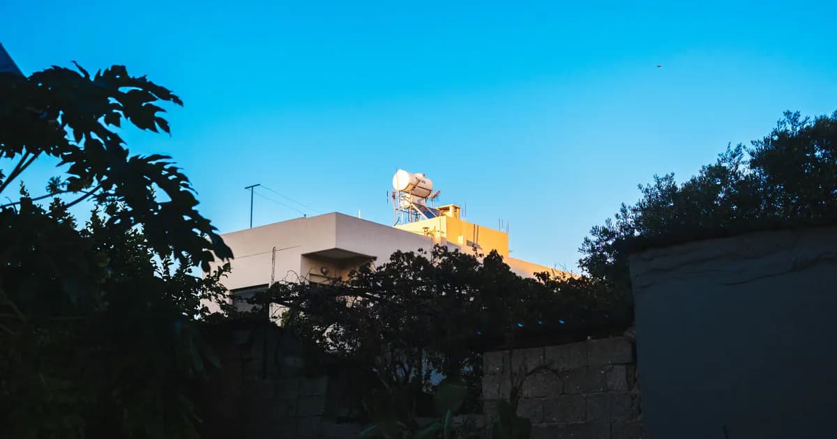 Low angle view of a building with a satellite dish under a clear blue sky, surrounded by trees
