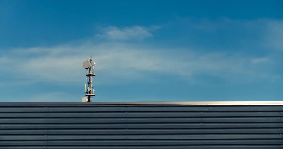 A modern telecommunication tower stands against a clear blue sky
