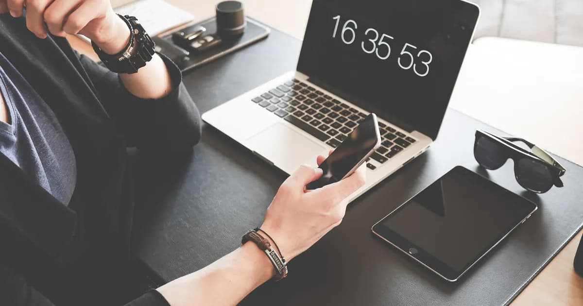 A modern workspace featuring a laptop, smartphone, tablet, and sunglasses
