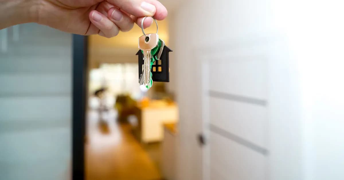 A hand holding house keys inside a modern apartment