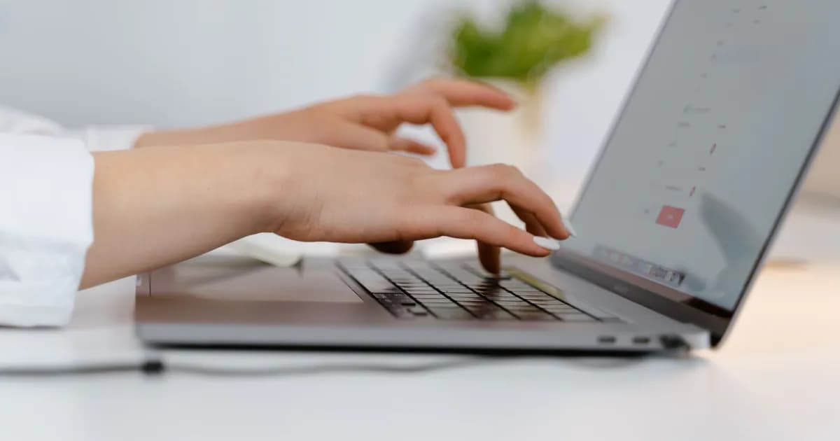 Hands typing on a laptop keyboard