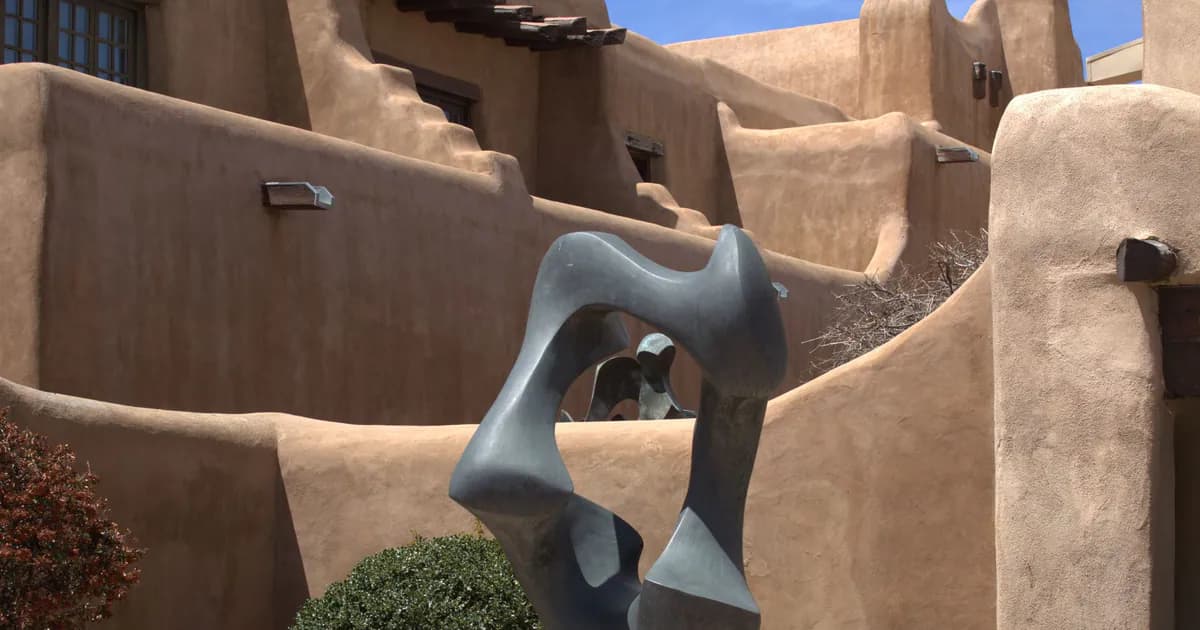 Modern abstract sculpture set against Santa Fe's iconic Pueblo Revival architecture