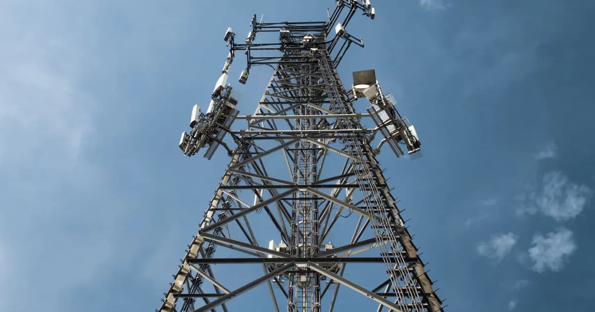 A low-angle shot of a tall metal communications tower with multiple antennas against a clear blue sky