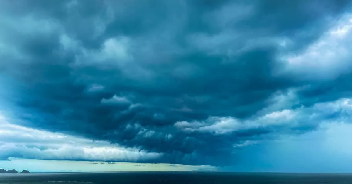 A dramatic formation of dark storm clouds hovering over a vast ocean expanse
