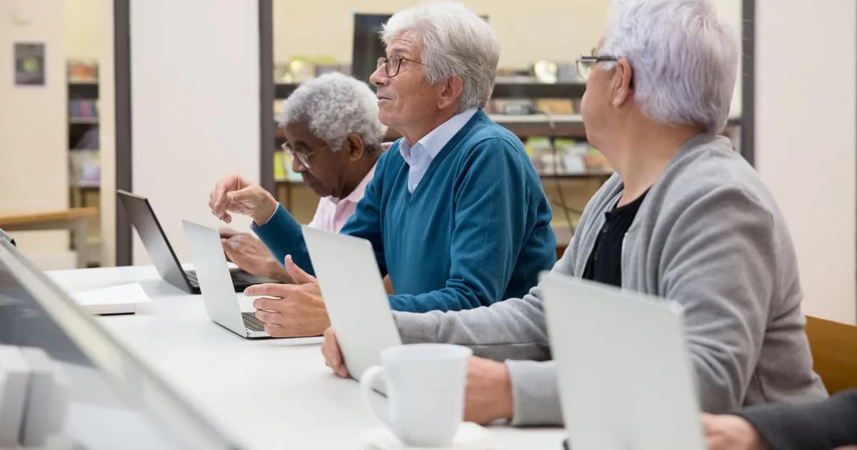Elderly men using laptops in a modern tech class, learning digital skills