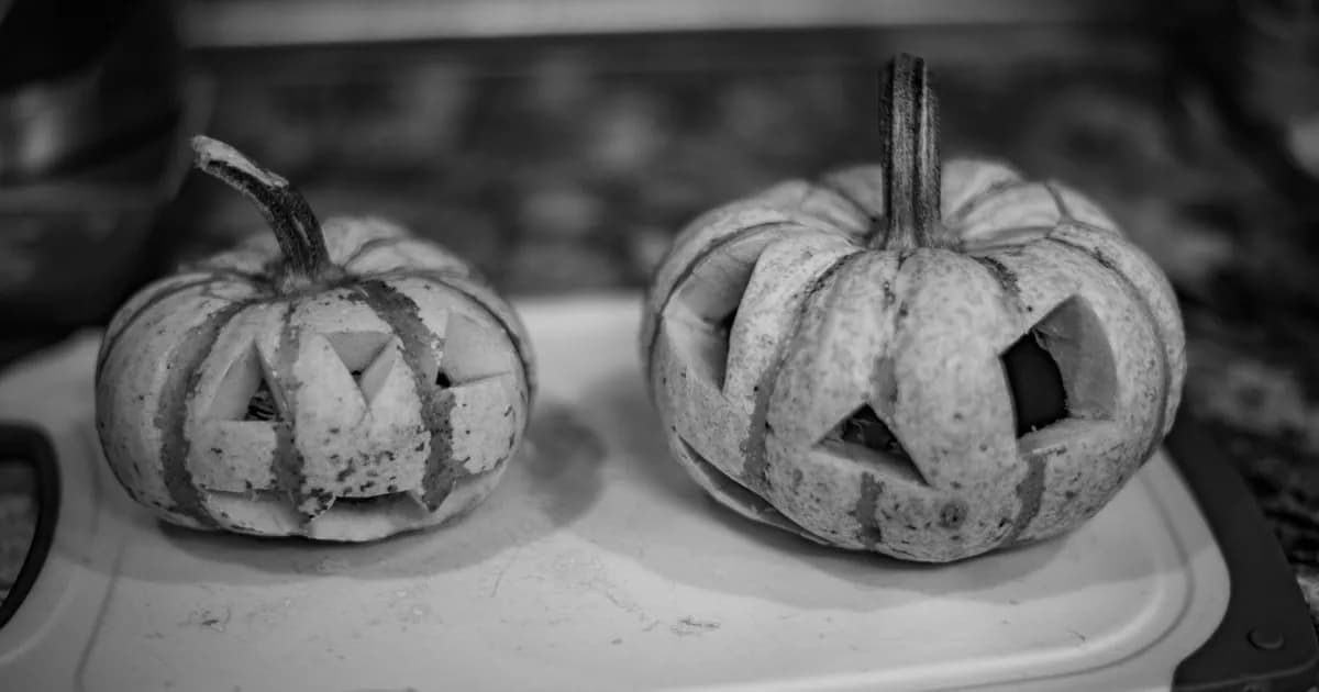 Monochrome image of carved pumpkins on a chopping board exuding a classic Halloween vibe