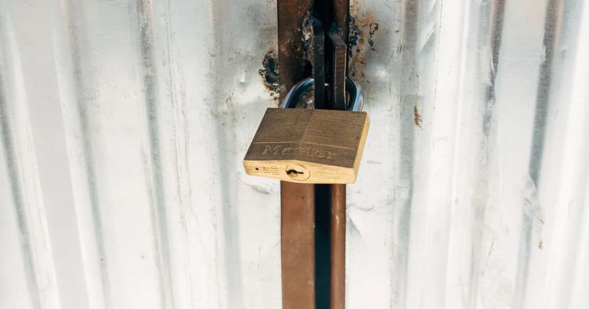 A sturdy padlock securing a metallic gate