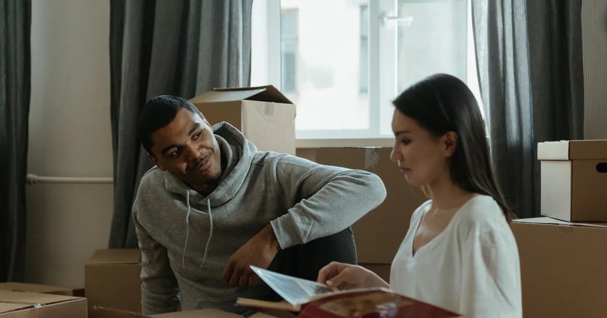 A couple exploring their new home while unpacking boxes and looking at a photo album