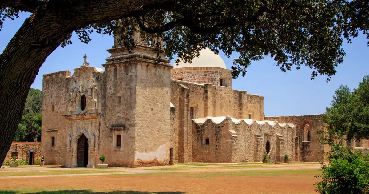 Statue of an old mission with lush trees in San Antonio