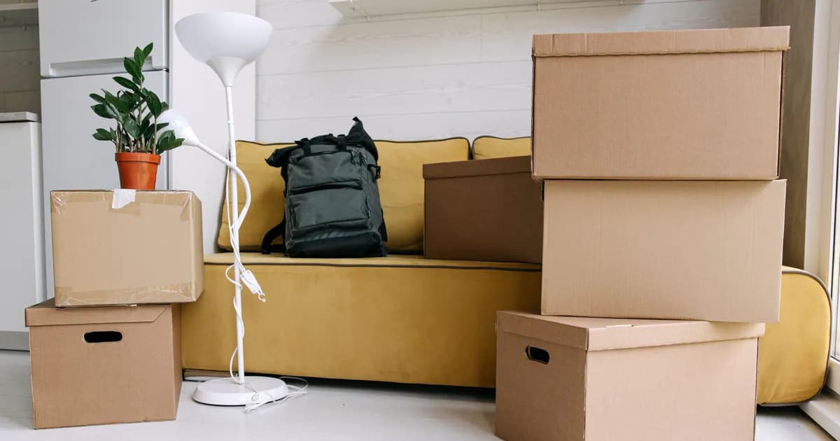 Cardboard boxes and a backpack in a cozy living room signify moving day excitement