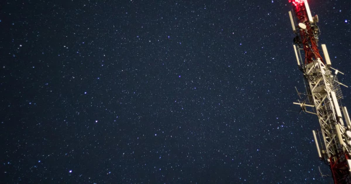 A starry night sky featuring a lit radio tower