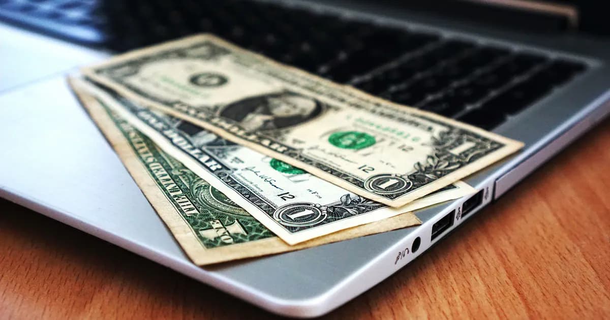Close-up of US dollar bills placed on a laptop symbolizing digital finance and economy