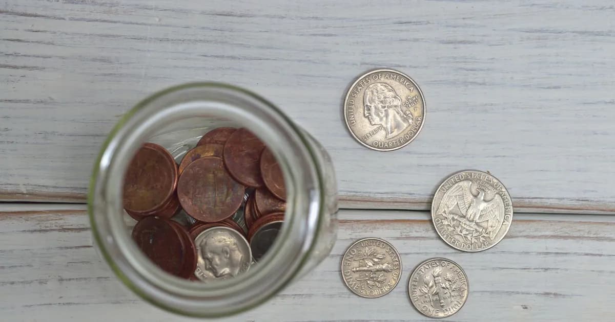 Top view of a jar filled with coins placed on a wooden table