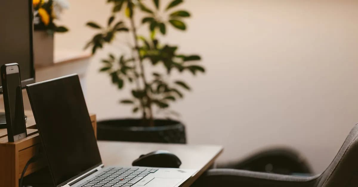 A cozy home office workspace with a laptop, headphones, and a plant. Ideal for remote work
