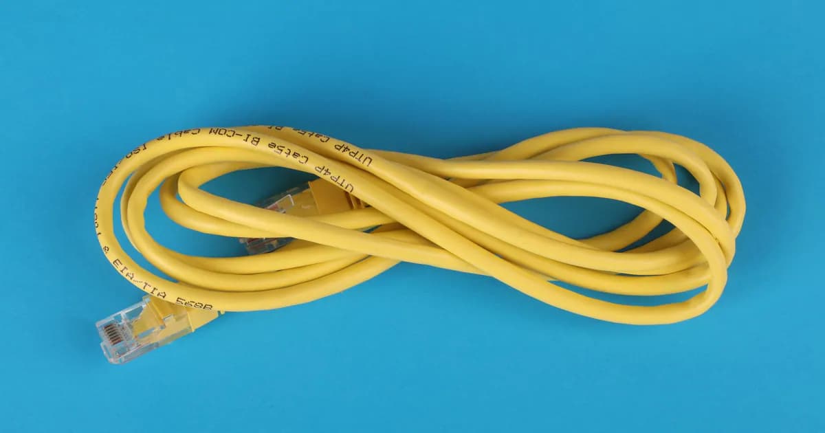 High-angle view of a yellow ethernet cable on a bright blue background