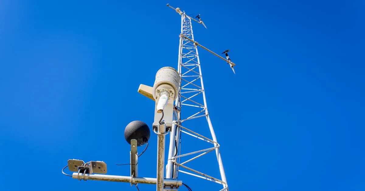 Close-up view of a communication tower with antennas under a clear blue sky