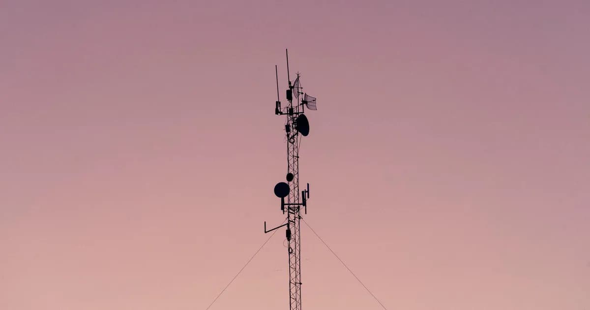 A tall telecommunication tower silhouetted against a clear dusk sky