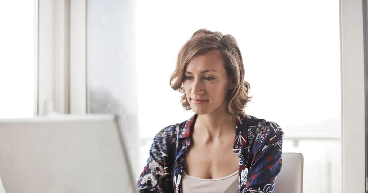 A woman typing on a laptop in a bright, modern home office setting
