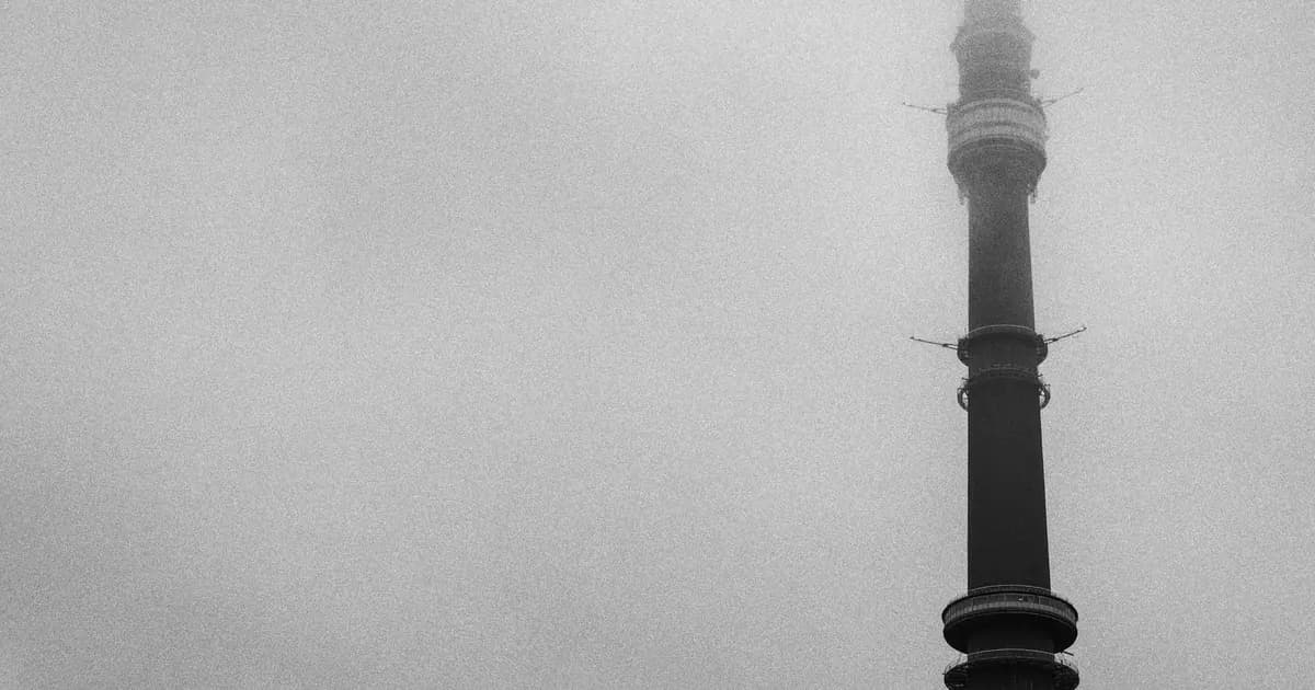 Black and white view of a tall high rise tower partially covered in fog