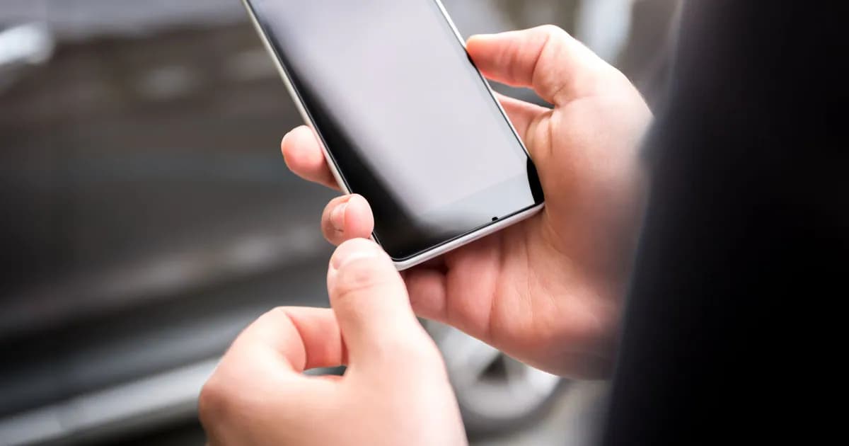 Close-up of hands holding a smartphone outdoors during the day