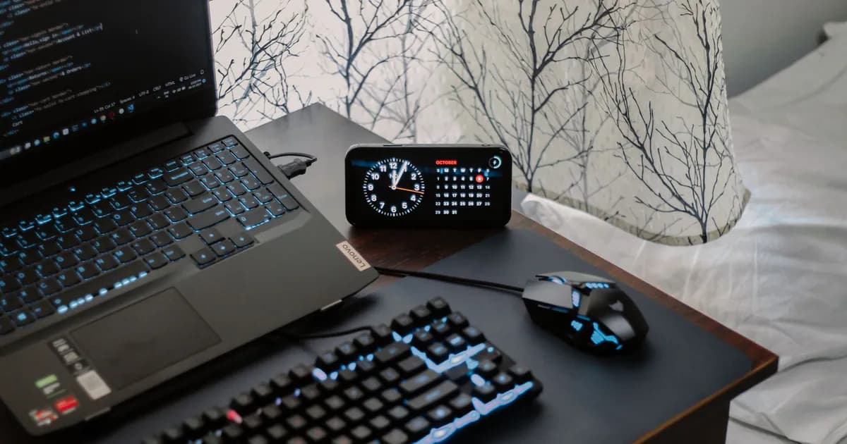 A modern workspace featuring a laptop, digital clock, gaming mouse, and keyboard